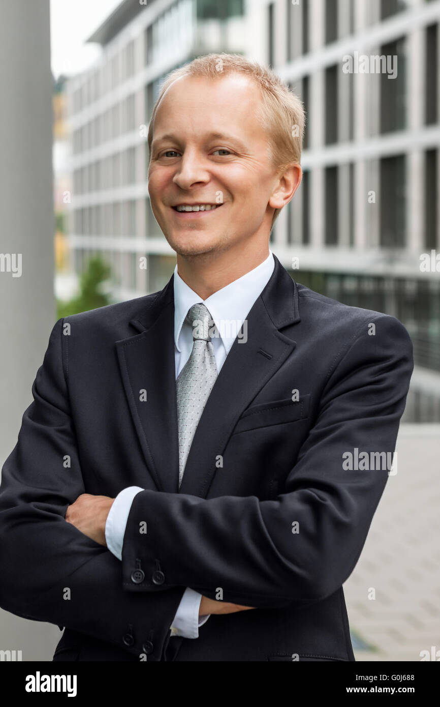 Sonriendo próspero hombre de negocios en traje negro outdoor Foto de stock