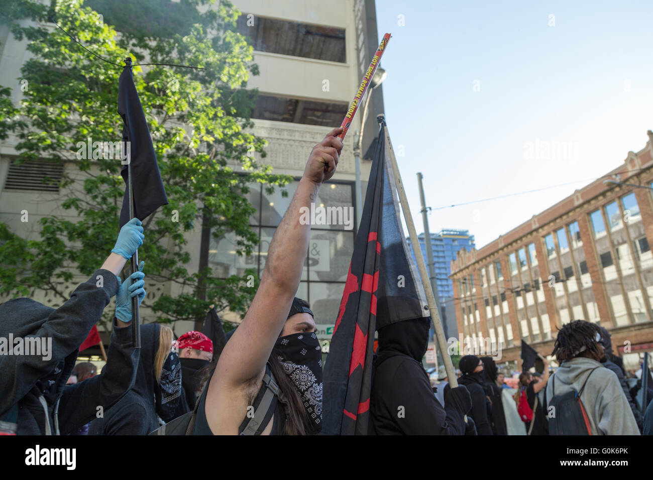 Seattle, EE.UU.. El 1 de mayo de 2016. Los manifestantes y la policía Anti-Capitalists marzo, uno de ellos se dispara un cohete en el aire. Foto de stock
