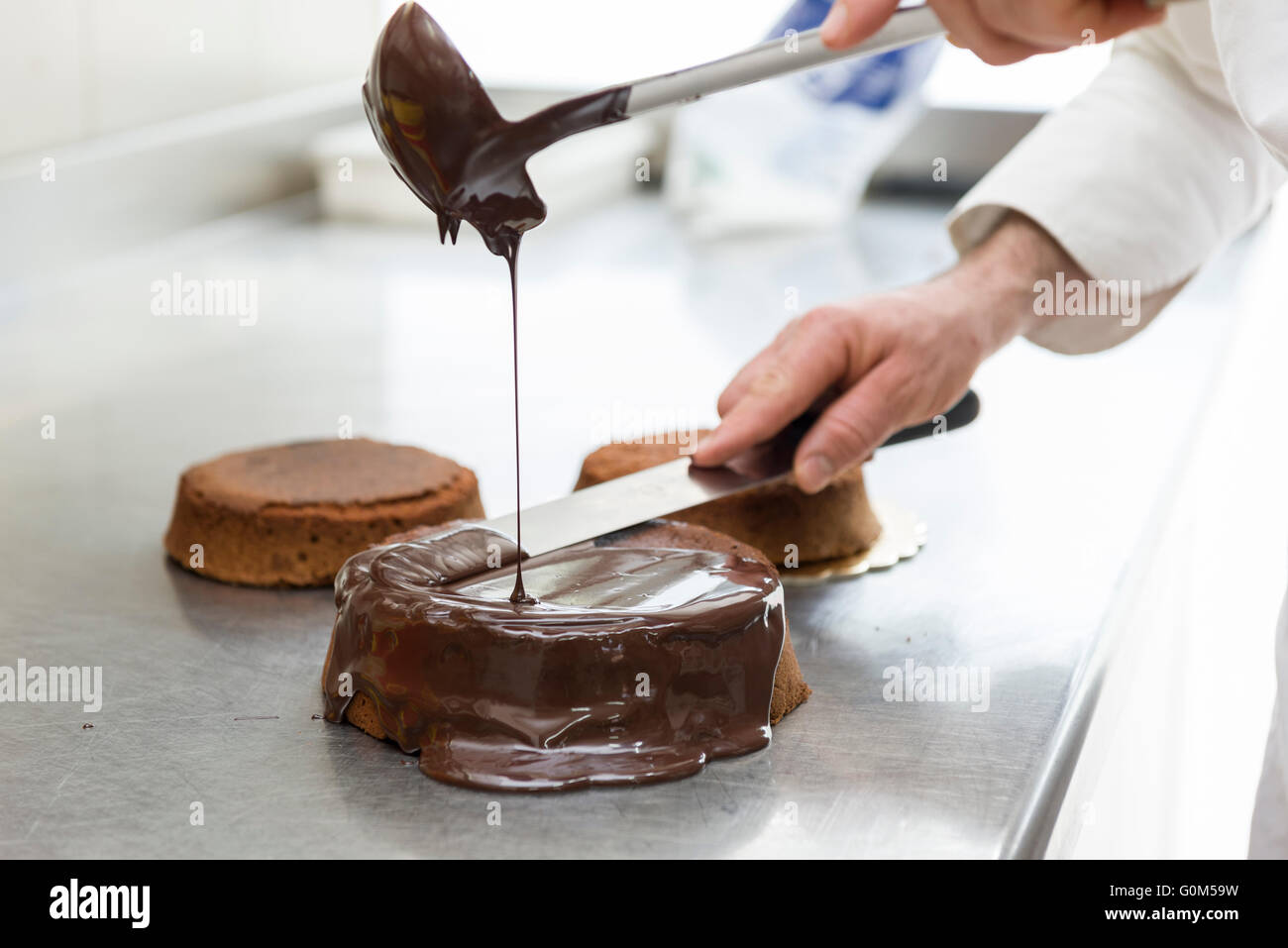Chef pastelero cubriendo torta con chocolate derretido Foto de stock