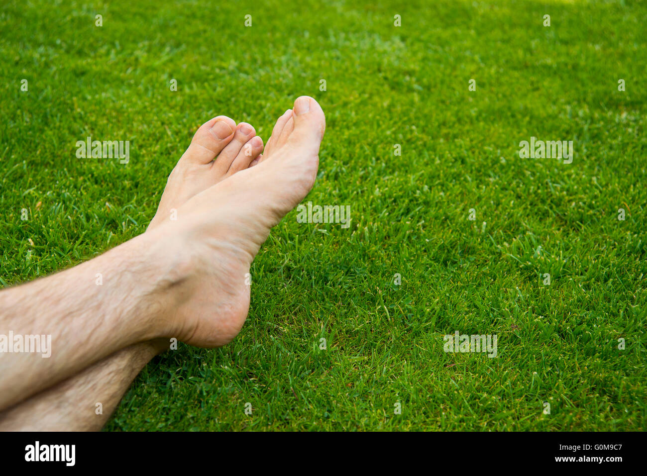 Los pies del hombre descansando sobre la hierba. Foto de stock