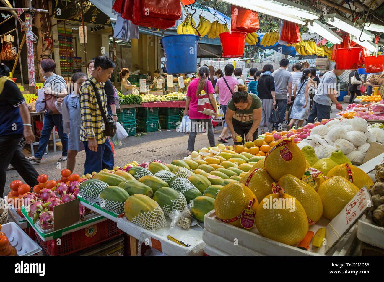Personas entre puestos llenos de frutas y verduras en el mercado de la calle en Tai Po, Hong Kong, China. Foto de stock