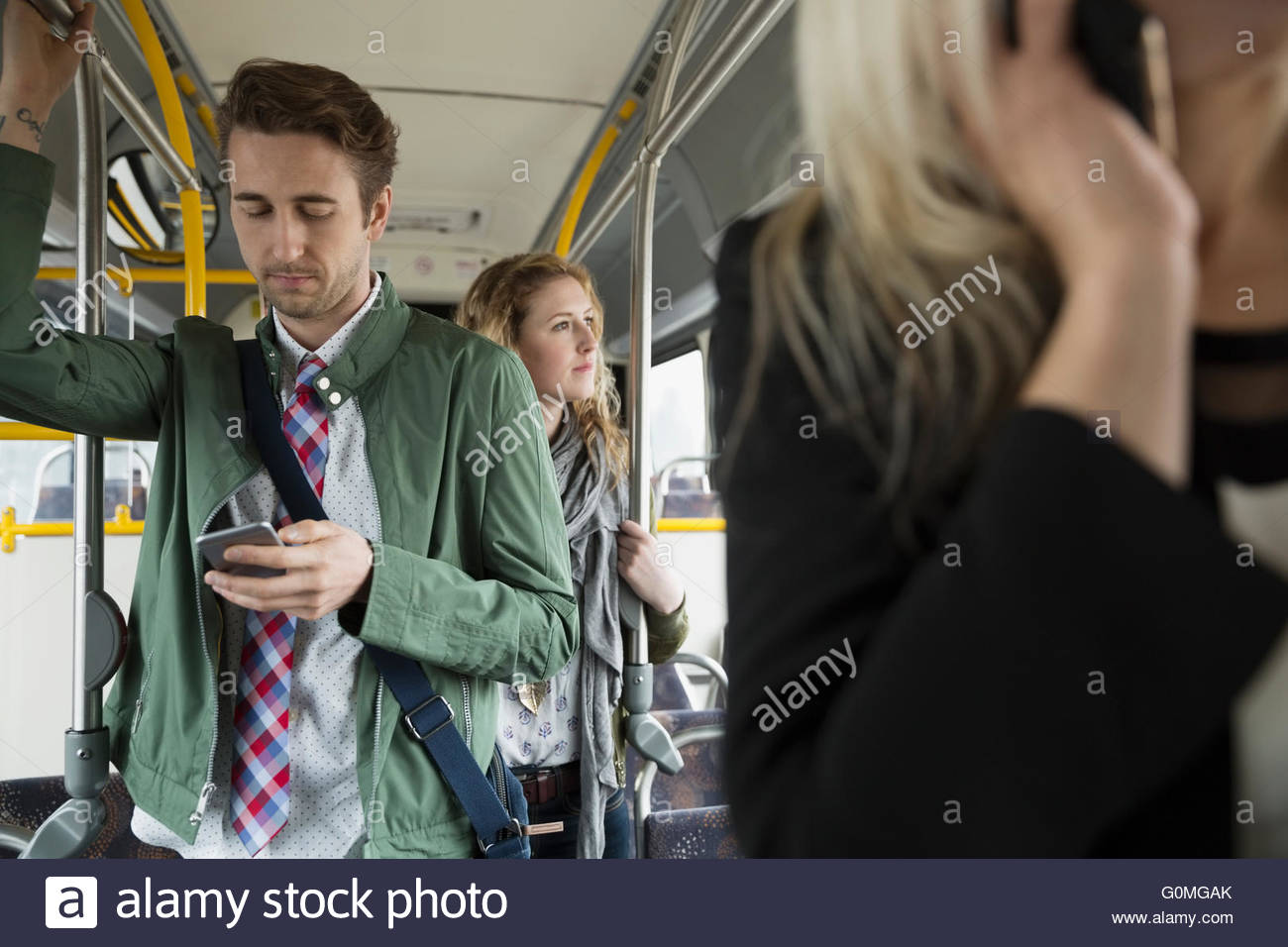 Empresario texting con teléfono celular de pie en el bus Foto de stock