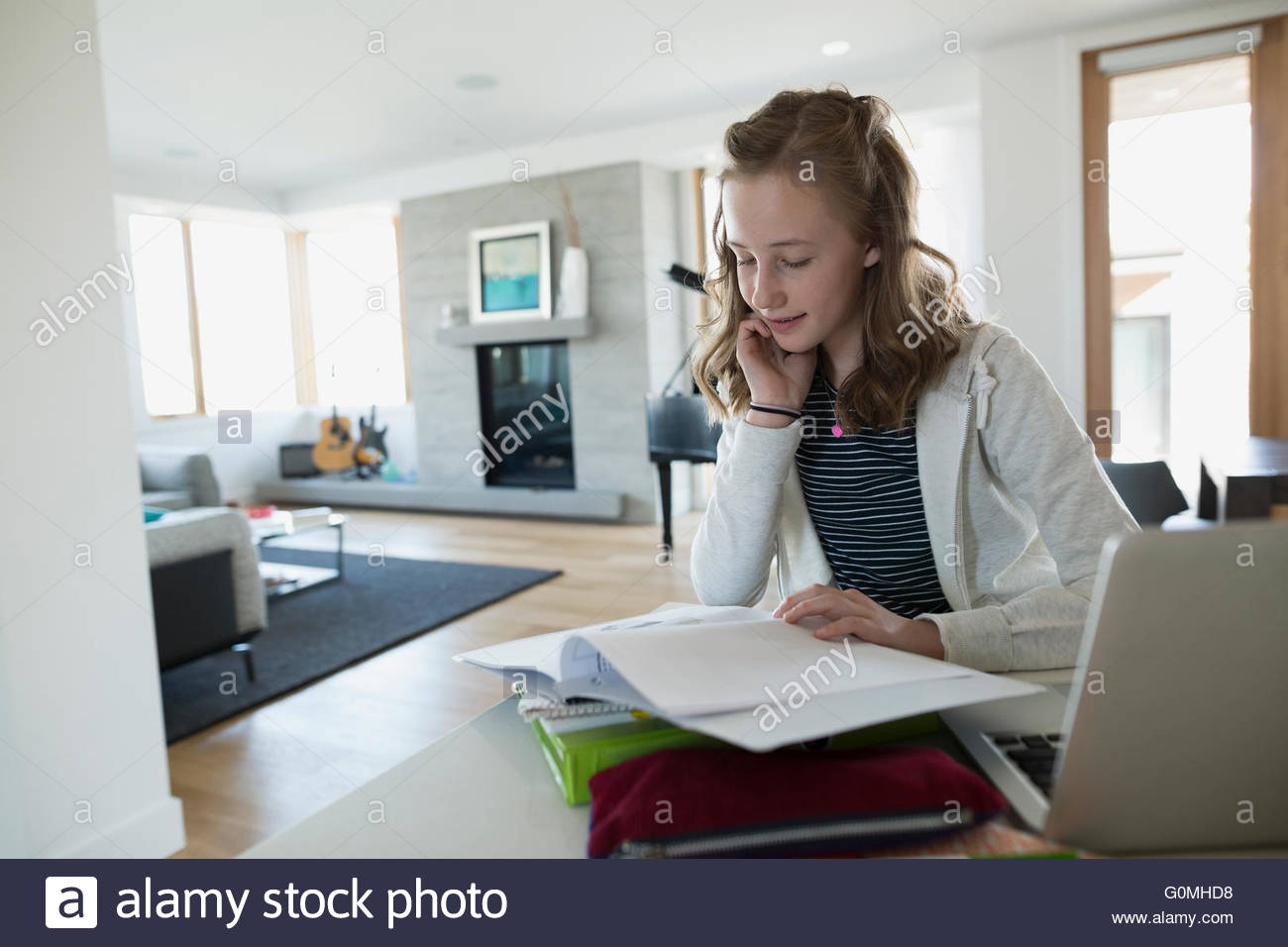Chica busca en la notebook haciendo los deberes cocina Foto de stock