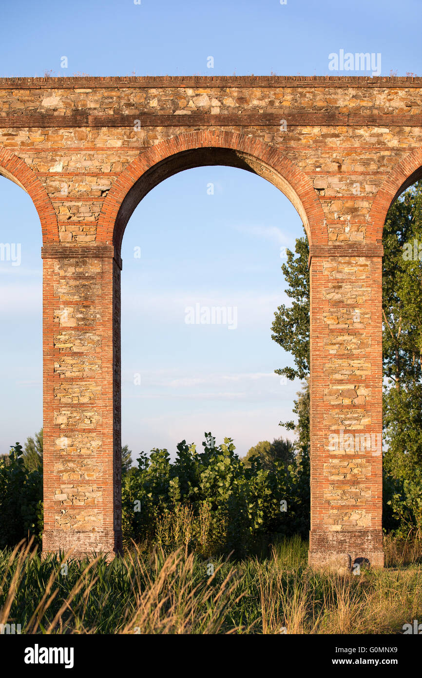 Sección de arco del acueducto Nottolini en Toscana, cerca de Lucca, Italia. Cálida luz del atardecer. Texturas y tonos clásicos toscanos. Foto de stock