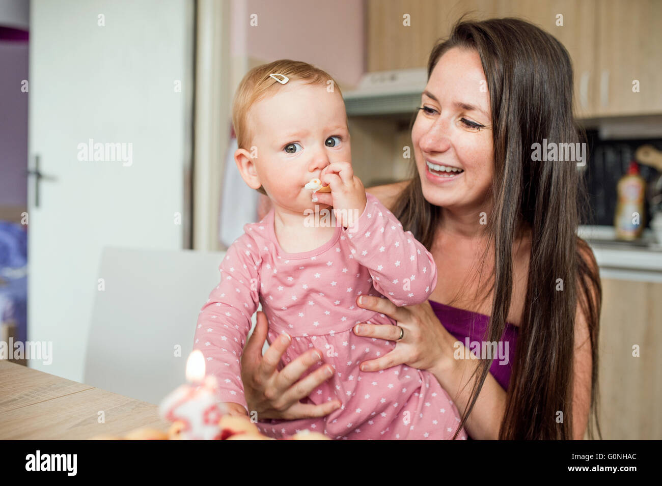 Madre sosteniendo a su hija comiendo pastel de cumpleaños Foto de stock