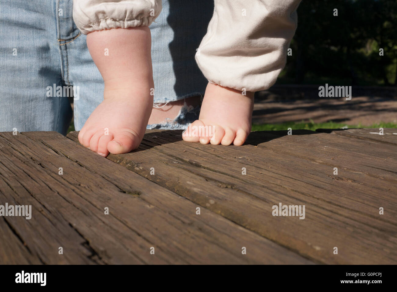 Los descalzos un bebé haciendo sus primeros sobre fondo de madera desgastada. Luz natural Fotografía de stock - Alamy