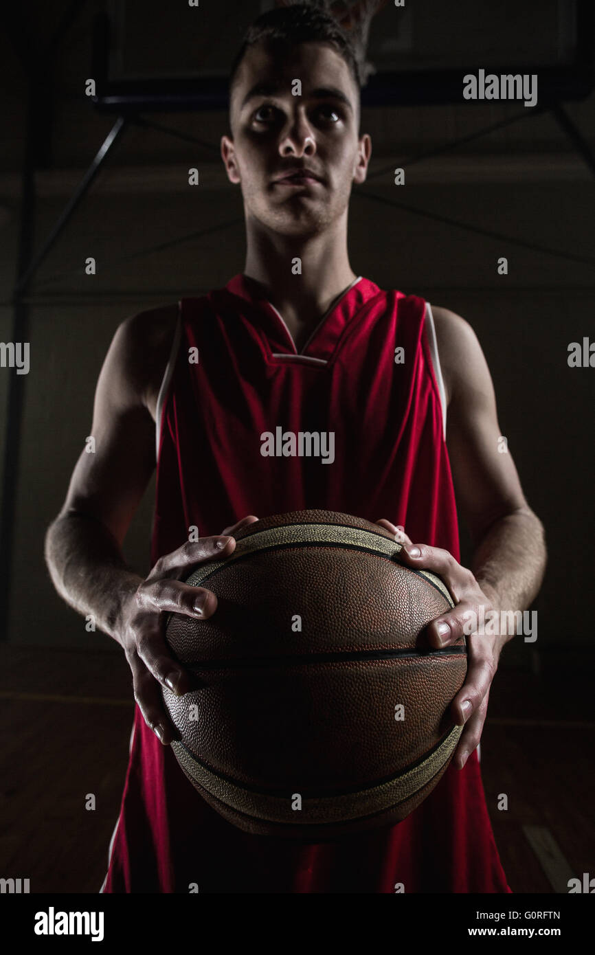 Retrato del jugador de baloncesto, nunca sonreían y sosteniendo una pelota de baloncesto Foto de stock