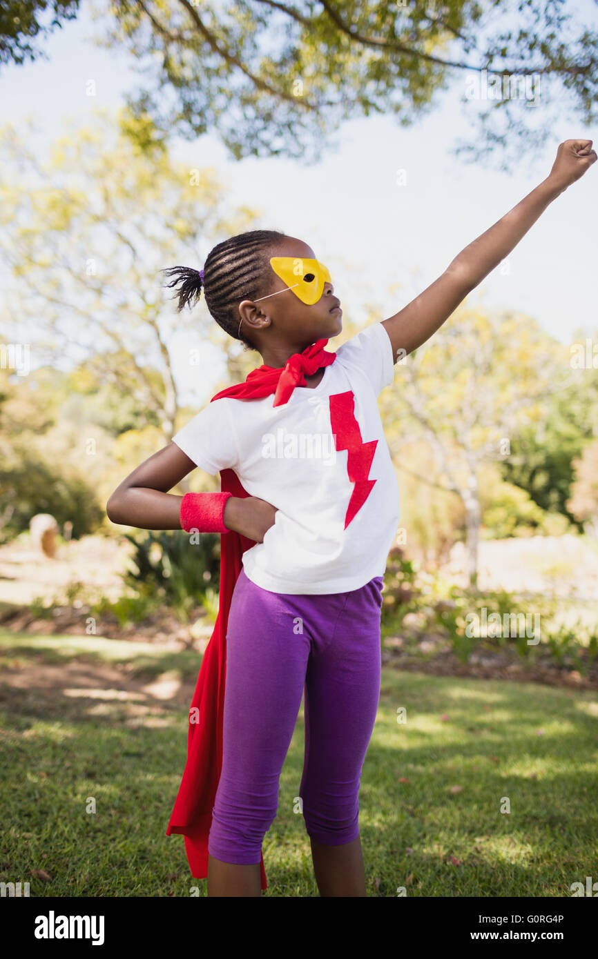 Una niña pretendiendo volar con el traje del superhéroe Foto de stock