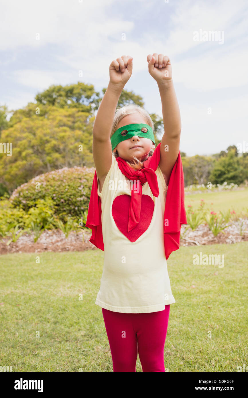 Little Girl fingiendo fingiendo volar con el traje del superhéroe Foto de stock