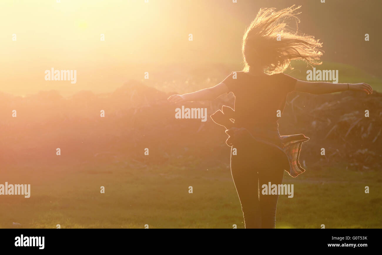 Chica saltando en una hermosa puesta de sol Foto de stock
