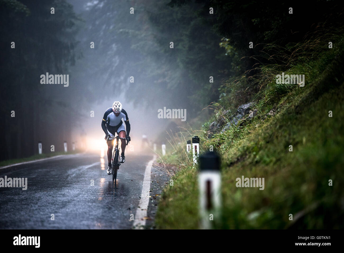 Hombre ciclismo en carretera mojada en la lluvia, Salzburgo, Austria Foto de stock