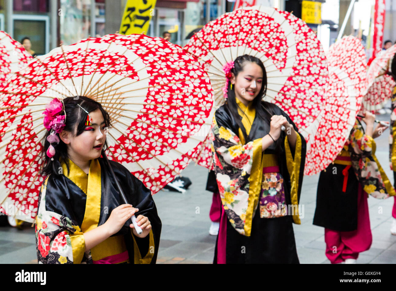 Yosakoi festival japonés. Fila de niños, en yukata negro, sosteniendo  sombrilla roja y blanca sobre el hombro, mientras se realiza la danza en  una galería comercial Fotografía de stock - Alamy