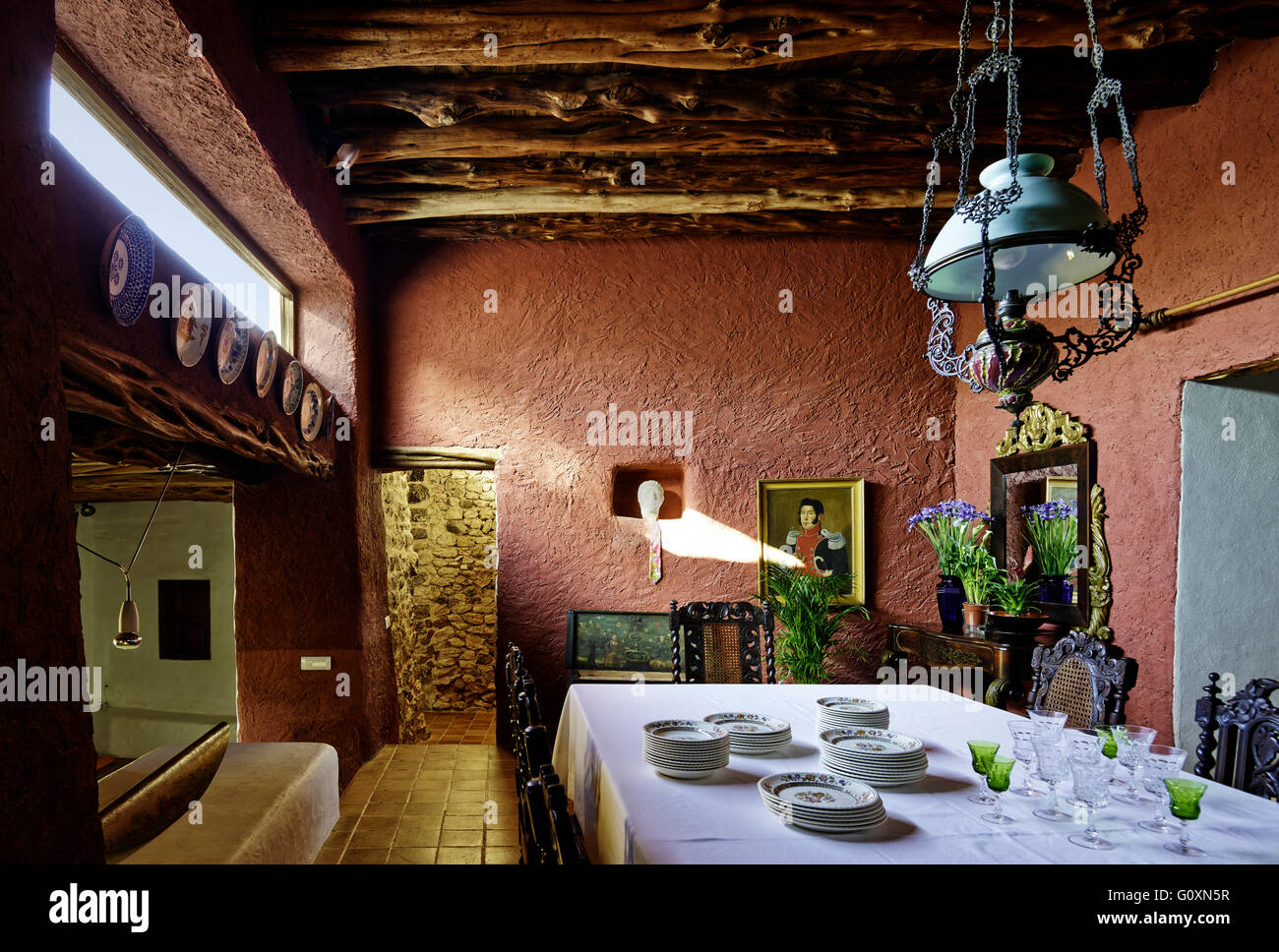 Casa de campo en Ibiza. Una villa comedor espacio con paredes rojas. Mesa con paño blanco y china. Foto de stock