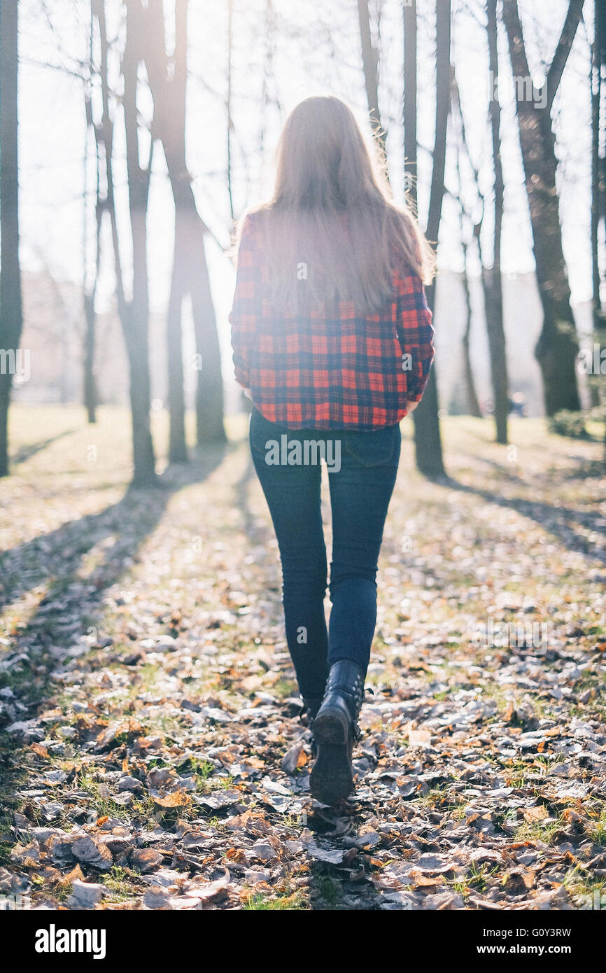 Vista trasera del hipster mujer caminando a través del bosque Foto de stock