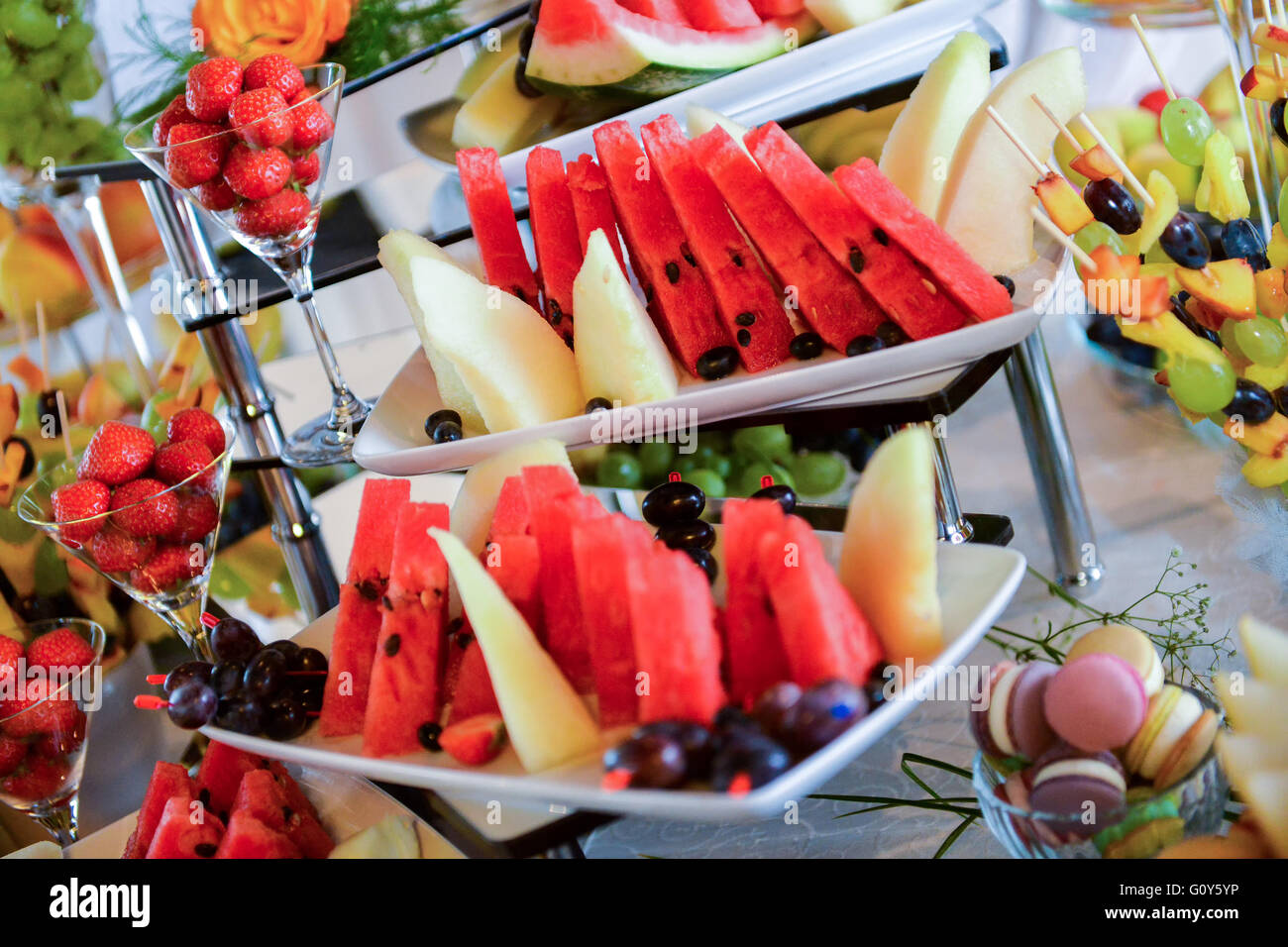 Placas con diferentes tipos de frutas: uvas, fresas, piña, sandía, albaricoques Foto de stock