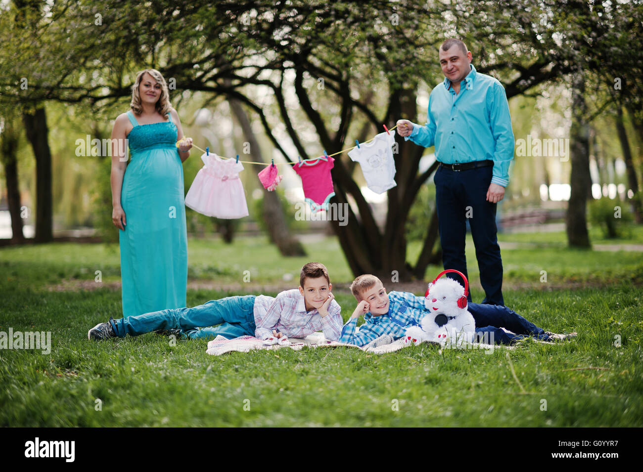 Feliz pareja embarazada con dos hijos la celebración de niñas ropa de bebé  en la cadena de fondo naturaleza primavera Fotografía de stock - Alamy