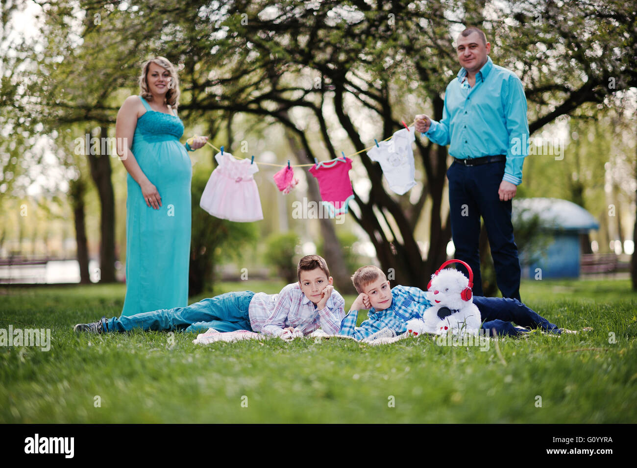 Feliz pareja embarazada con dos hijos la celebración de niñas ropa de bebé  en la cadena de fondo naturaleza primavera Fotografía de stock - Alamy