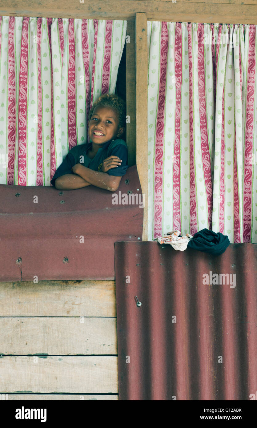 Chico en la ventana de casa simple, Owa Raha (Santa Ana), las Islas Salomón, en Melanesia Foto de stock