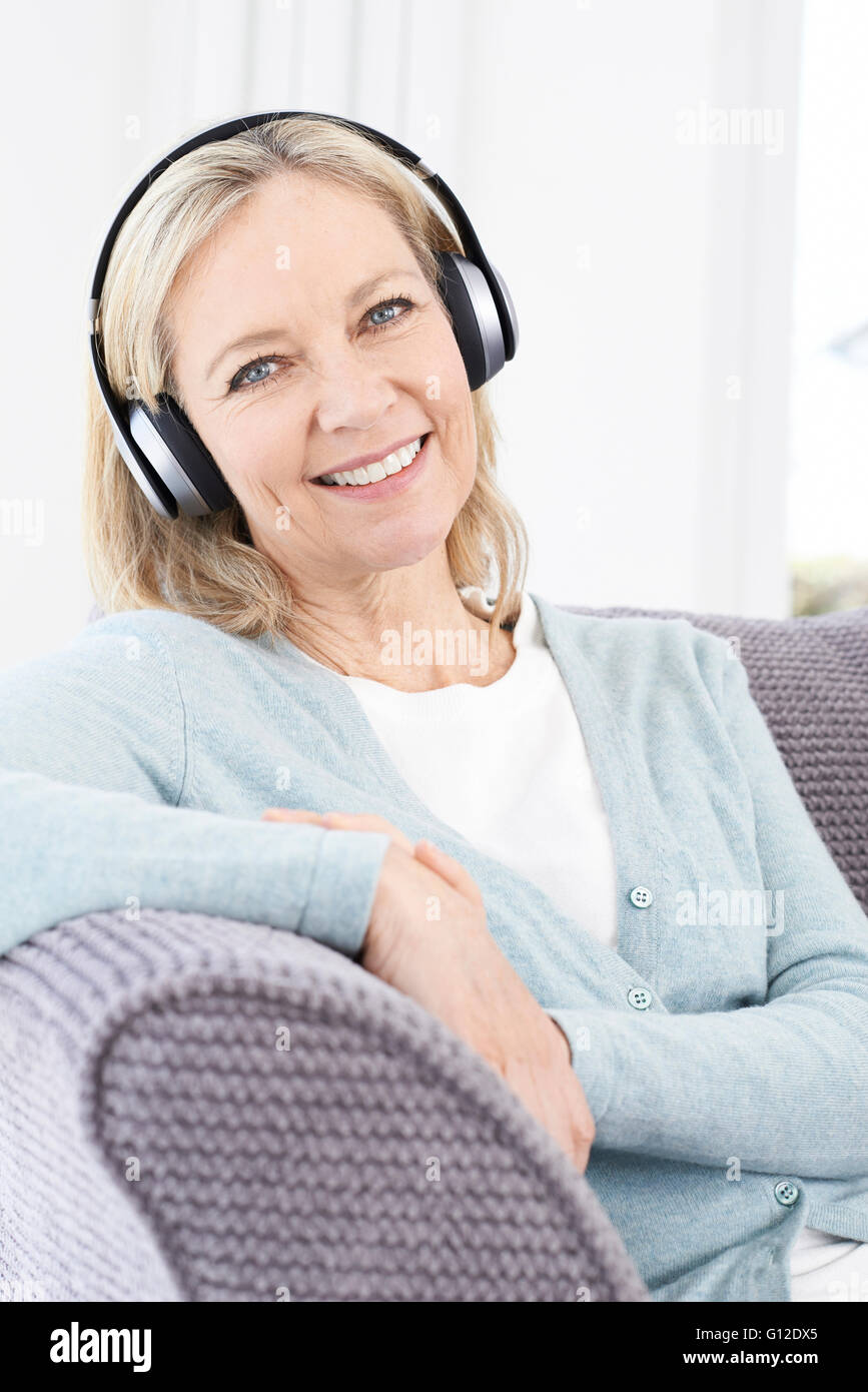 Mujer madura, escuchando música en auriculares inalámbricos Foto de stock