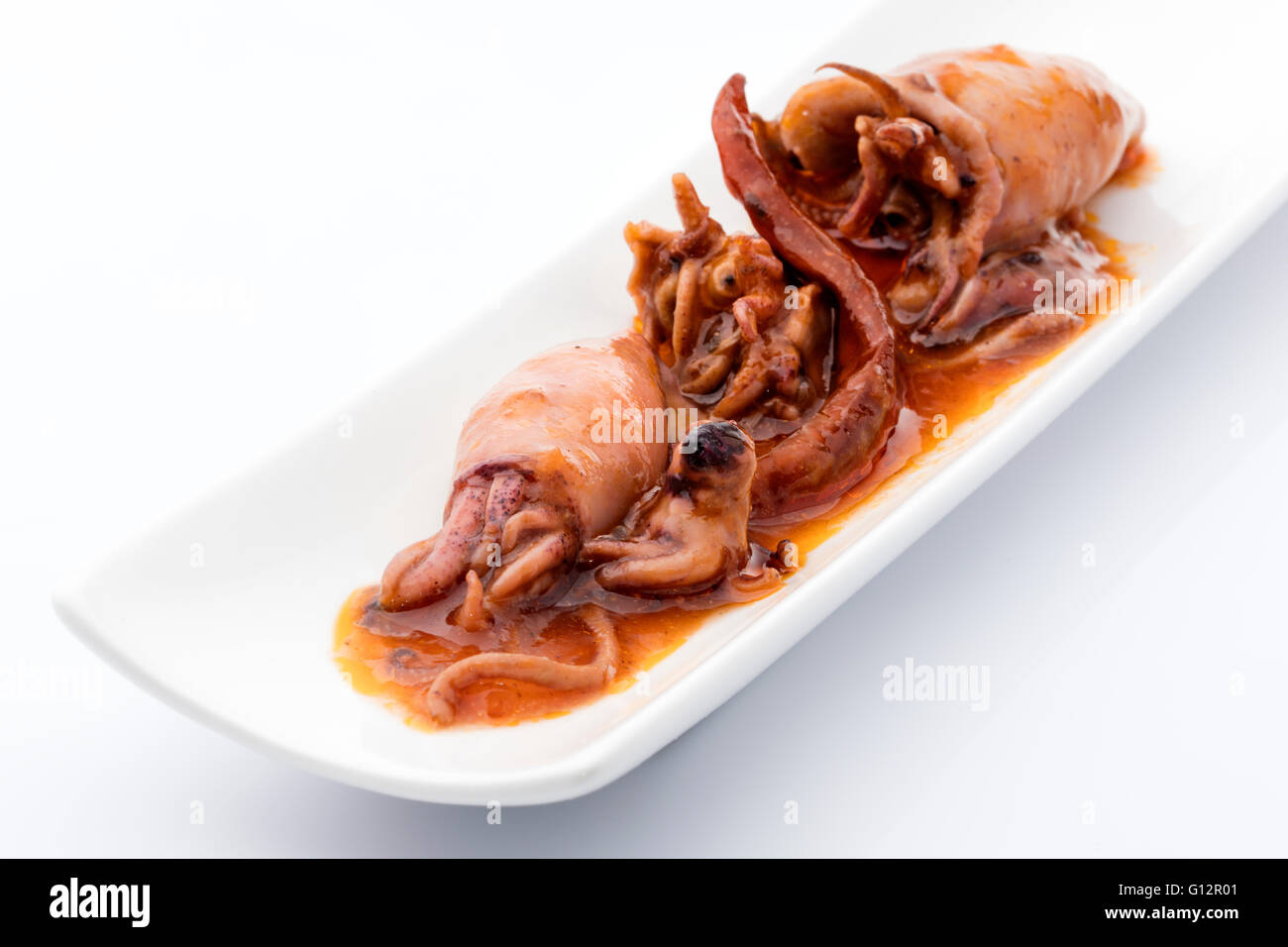 Snack calamares conservar en salsa de pimienta caliente sobre un fondo blanco. Foto de stock