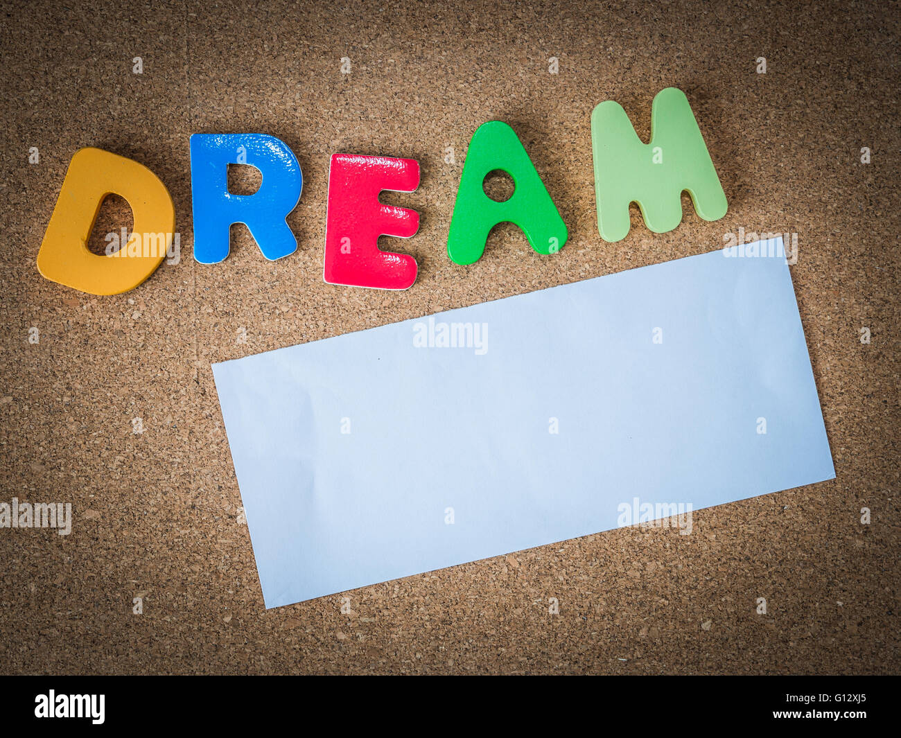 Palabra coloridas de madera soñar con un trozo de papel blanco en el tablero  de corcho Fotografía de stock - Alamy