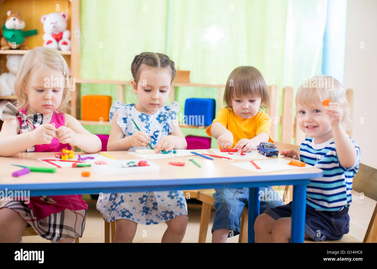 Grupo de niños aprendiendo artes y oficios en playroom con interés Foto de stock