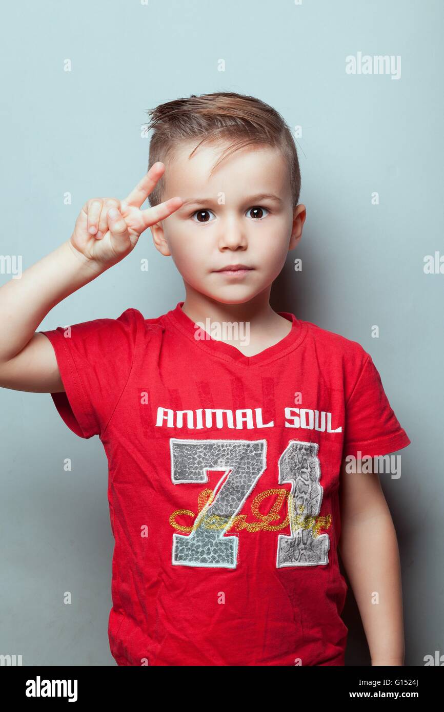 Retrato de un niño haciendo el signo de la V de la victoria con su mano, los ojos abiertos Foto de stock