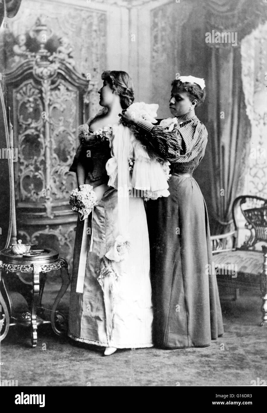 Maid ayudando mujer vestirse en vestido de noche. La moda es un estilo  popular o la práctica, especialmente en prendas de vestir, calzado,  accesorios, maquillaje, o muebles. Un vestido de noche o