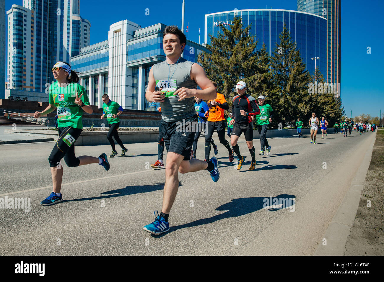 Grupo de atletas corredores corriendo por las calles de la ciudad con rascacielos en segundo plano. Foto de stock