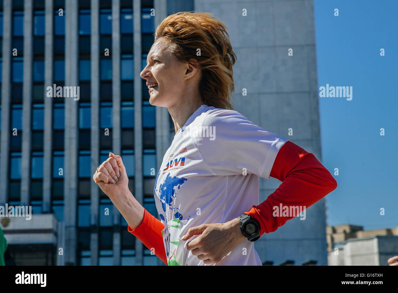 Mujer joven corre a través de la ciudad, una sonrisa en su cara durante el maratón de la ciudad de Foto de stock