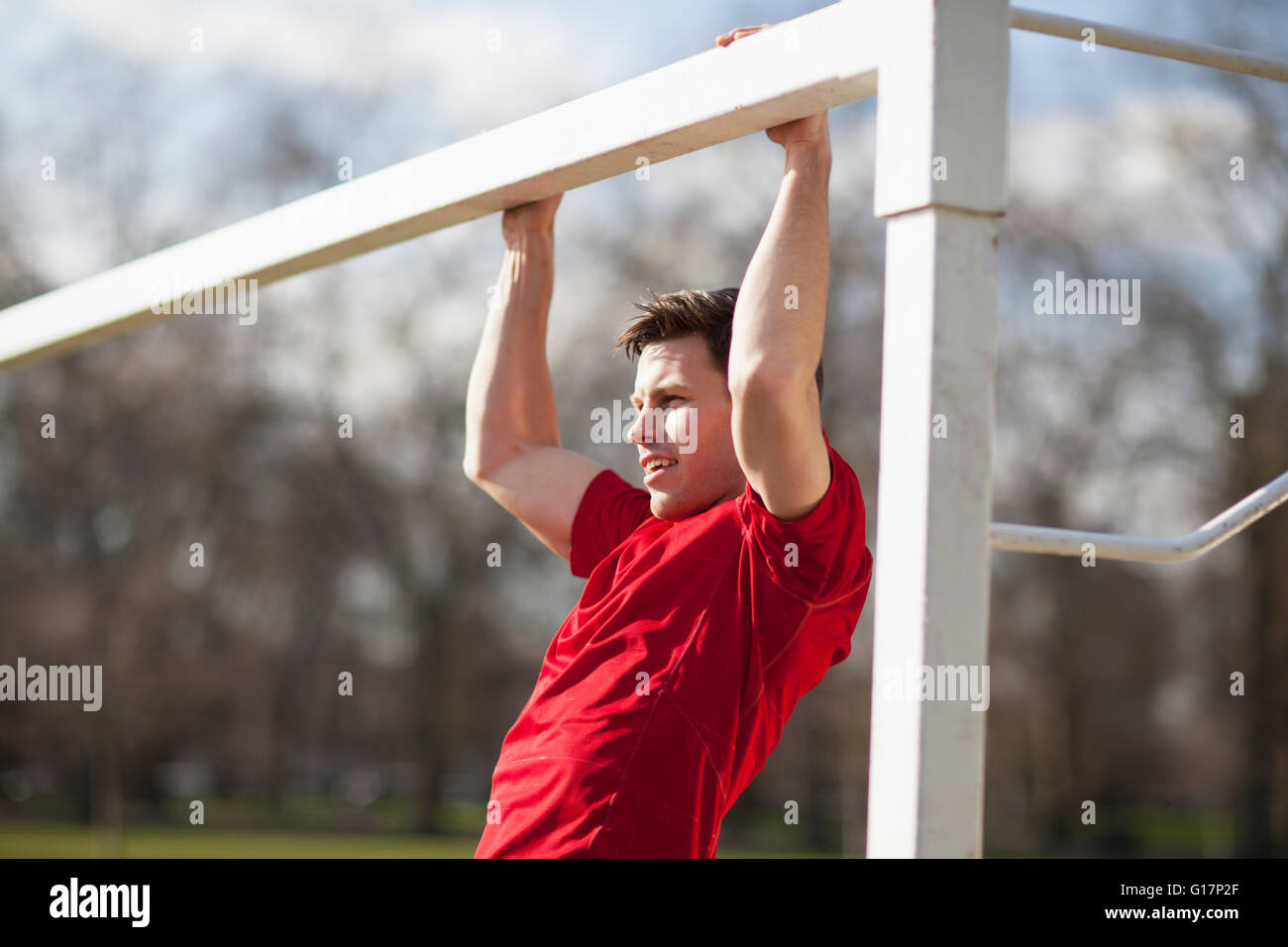 Joven haciendo tirar ups jugando field goal post Foto de stock