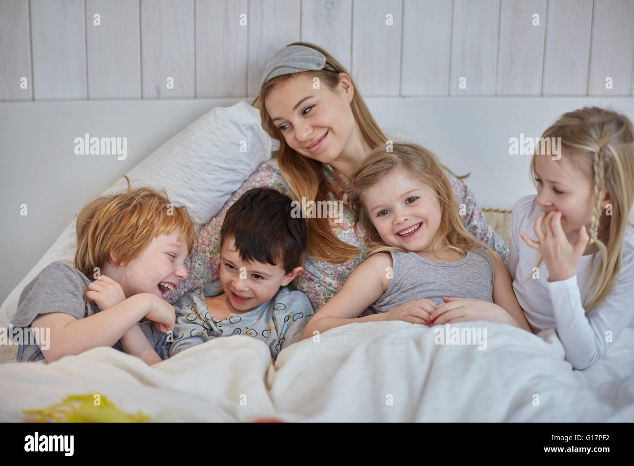 Madre e hijos juntos en la cama Foto de stock