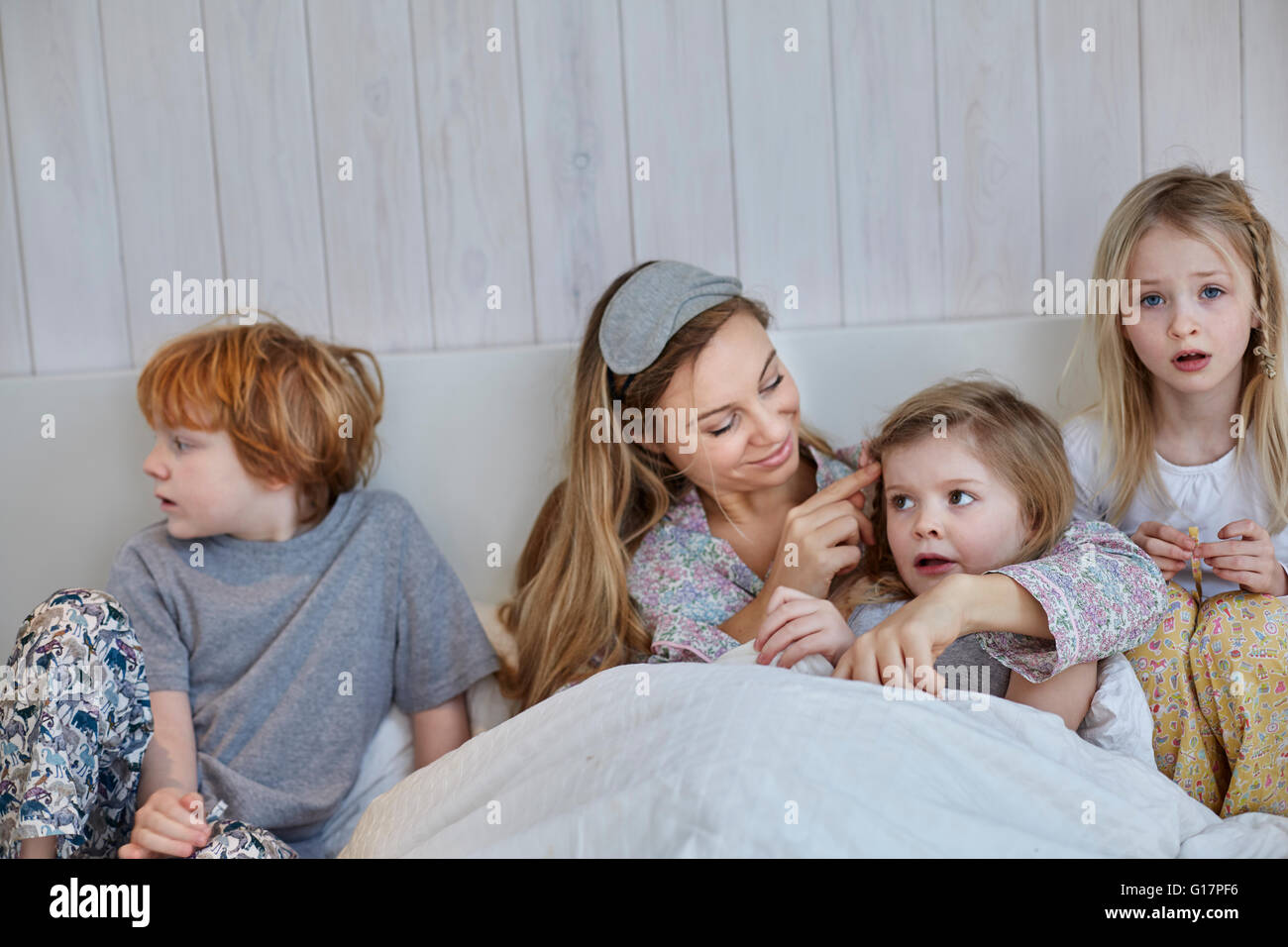 Madre e hijos juntos en la cama Foto de stock