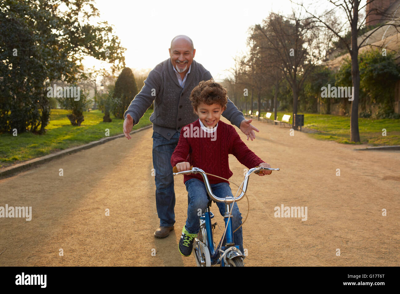 Enseñanza abuelo nieto para andar en bicicleta en el parque Foto de stock