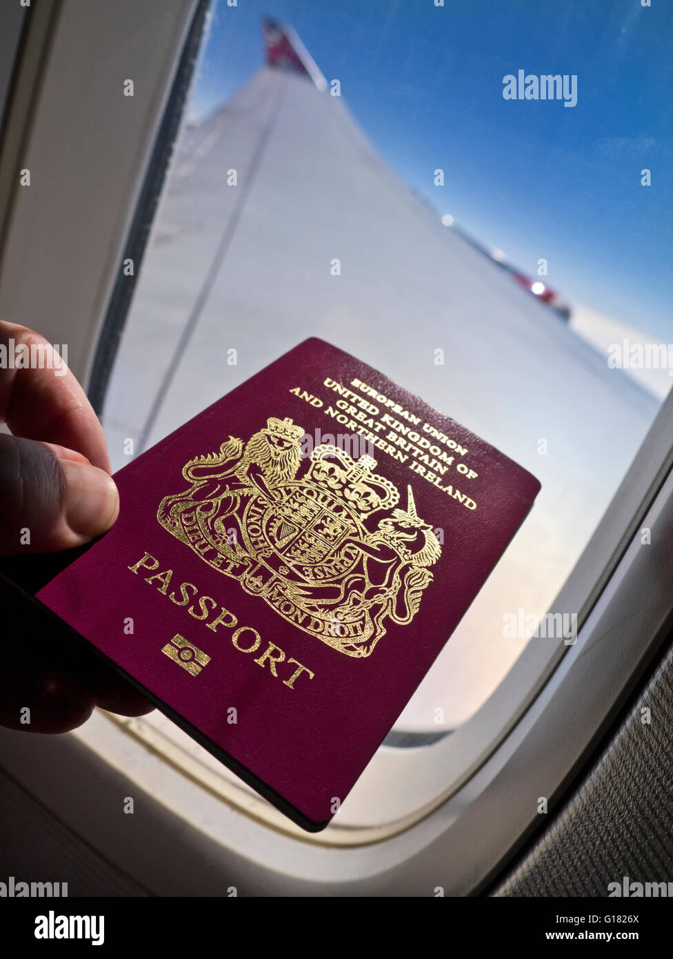 PASAPORTE VOLAR VACACIONES LIBERTAD concepto de viaje imagen biométrica británica pasaporte avión cabina con ventana ala y el cielo detrás en vuelo Foto de stock