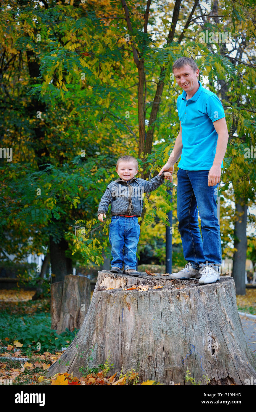 Padre e hijo de pie sobre un tocón en el parque Foto de stock