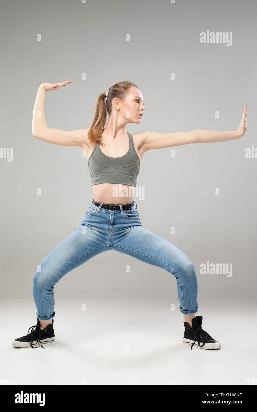 Chica en pose de artes marciales sobre fondo gris Foto de stock