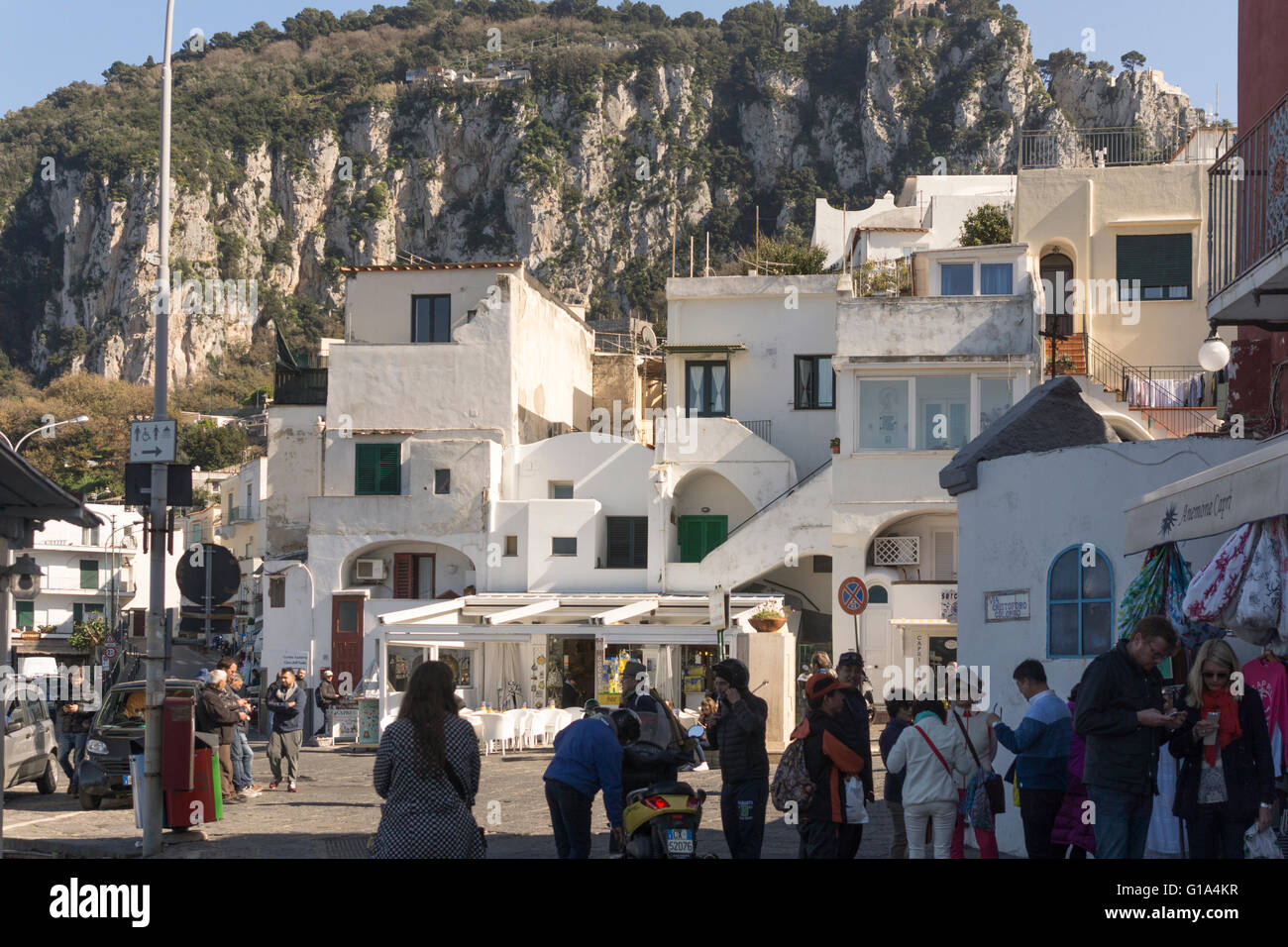 El sol de la mañana llega a los edificios blancos mediterráneos en el puerto de Marina Grande, donde los lugareños y turistas se mezclan. Isla de Capri, Italia Foto de stock