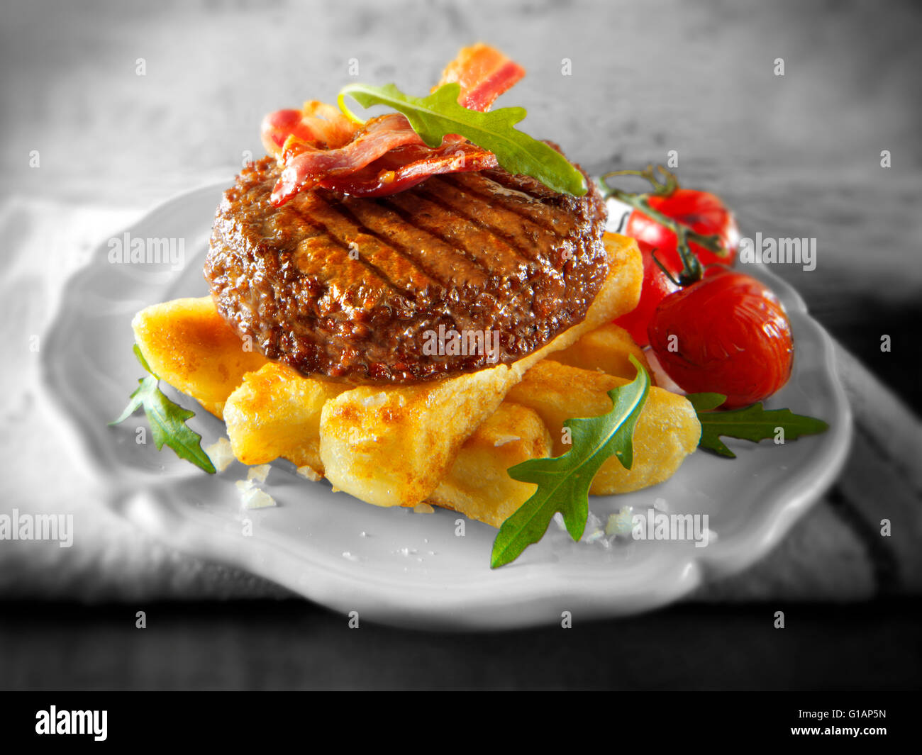 Char hamburguesa de carne a la parrilla o una hamburguesa y bacon con patatas fritas y ensalada troceada Foto de stock