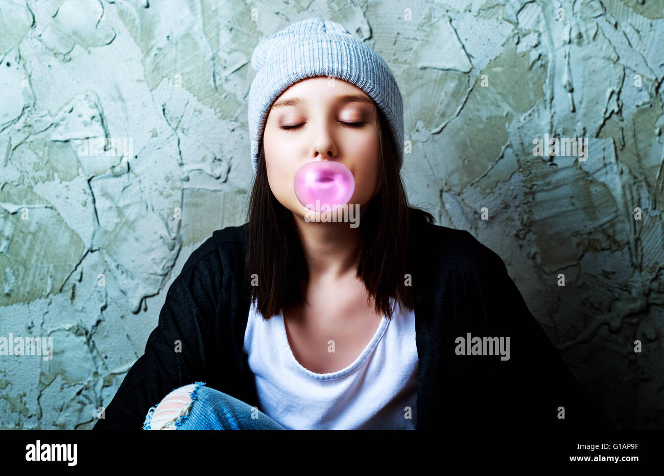 Adolescente con un chicle contra el viejo muro Foto de stock