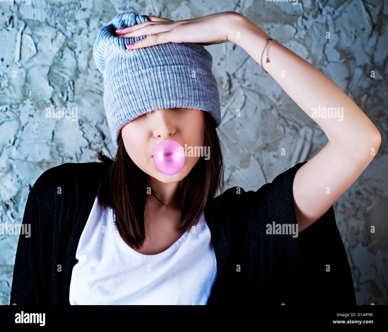 Adolescente con un chicle contra el viejo muro Foto de stock