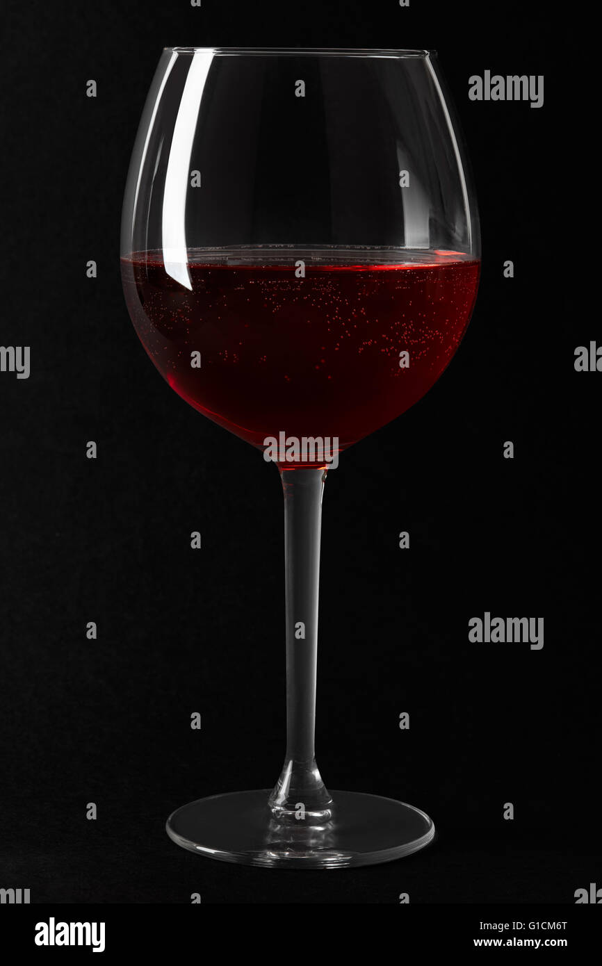 Copa de vino espumoso de color rojo sobre fondo negro Foto de stock