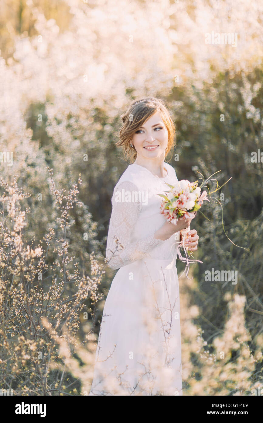 Hermosa joven rubia vestidos de novia vestido blanco con bouquet en la  floración en el prado. Disfruta de la naturaleza delicada niña primavera  Fotografía de stock - Alamy