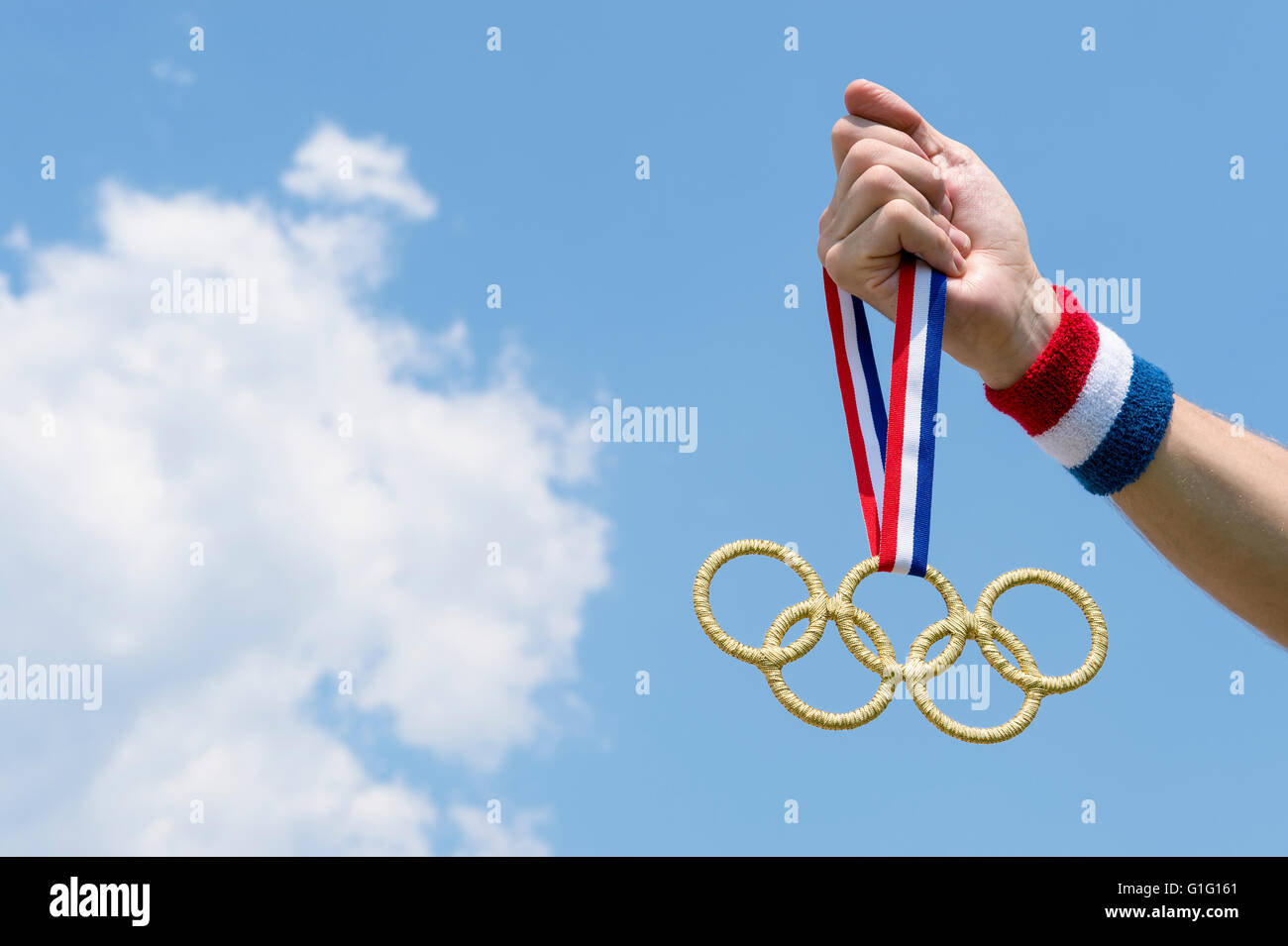 RIO DE JANEIRO.- El 4 de febrero de 2016: Mano con rojo, blanco y azul pulsera de oro sujetando los anillos olímpicos medalla colgando de la cinta. Foto de stock