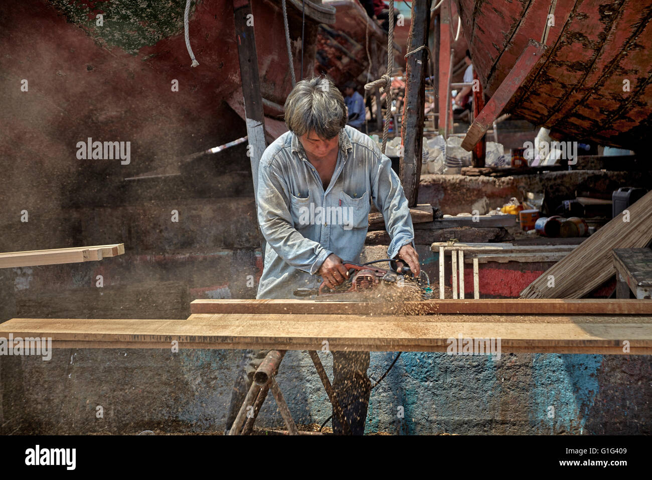 Carpintero trabaja con madera usando una herramienta eléctrica. Foto de stock