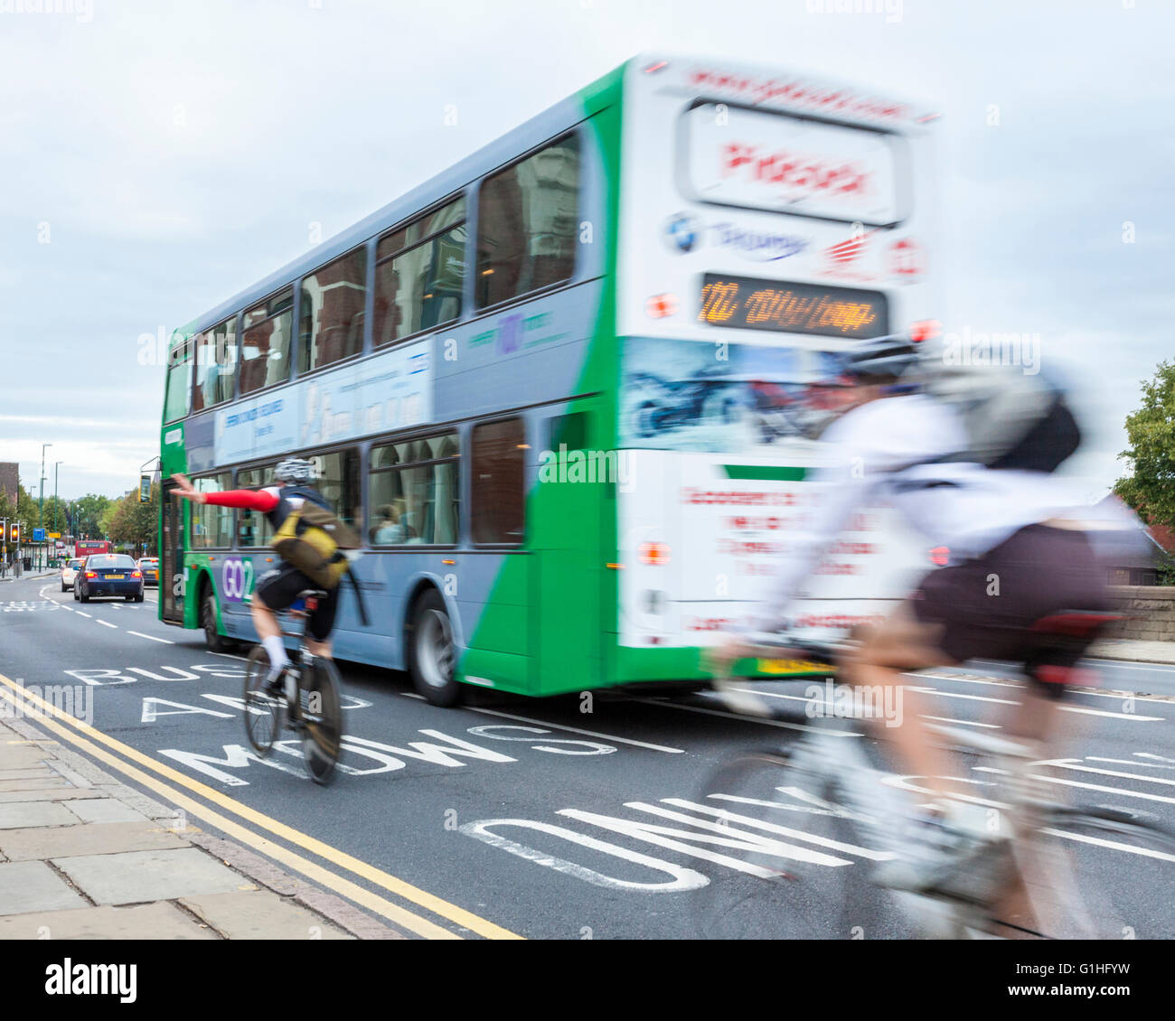 Ciclismo en el tráfico. Un autobús que pasaba por dos ciclistas en una concurrida calle de la ciudad, Nottingham, Inglaterra, Reino Unido. Foto de stock