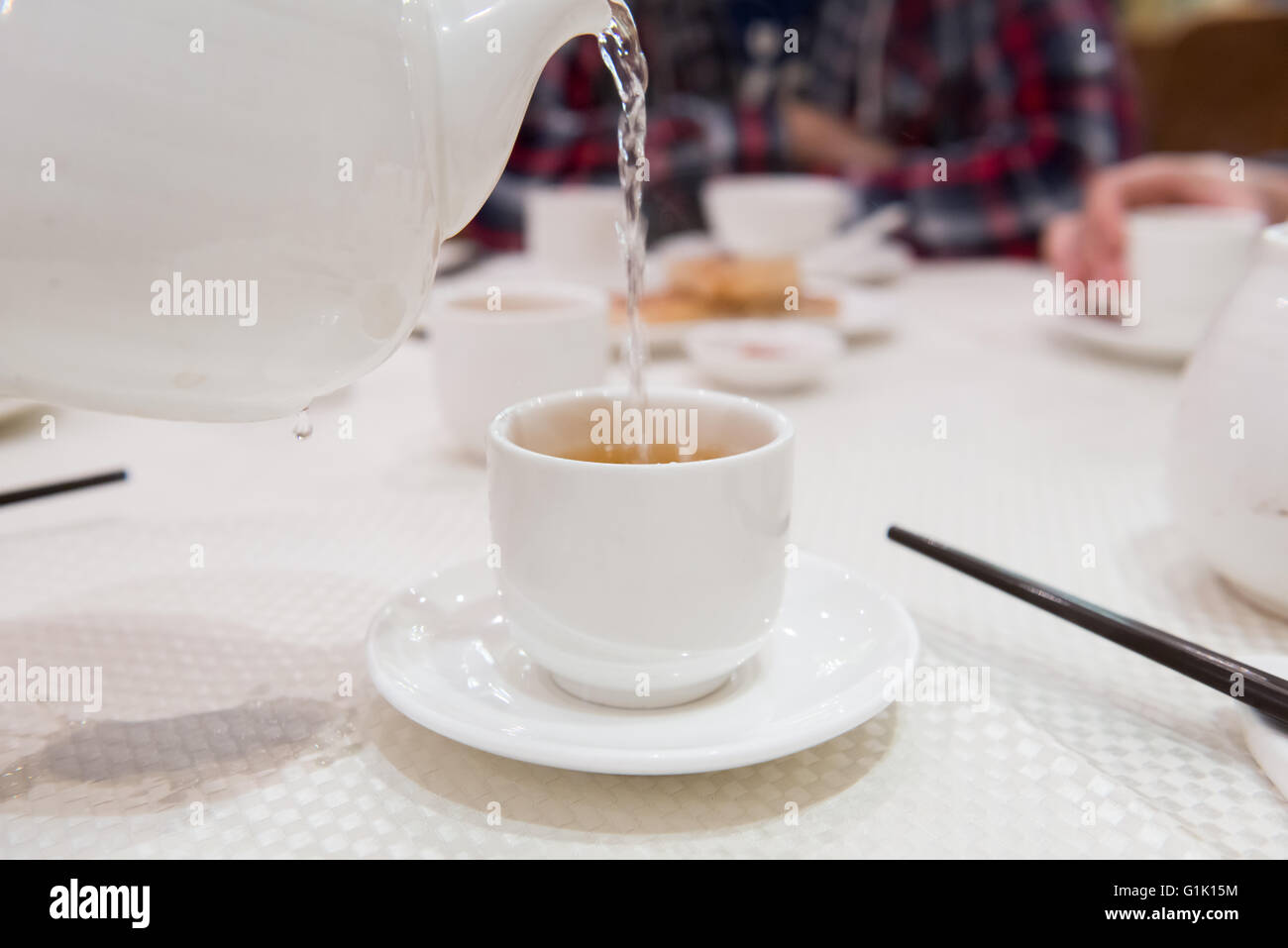 Vertiendo agua caliente en la taza de té en la mesa Foto de stock