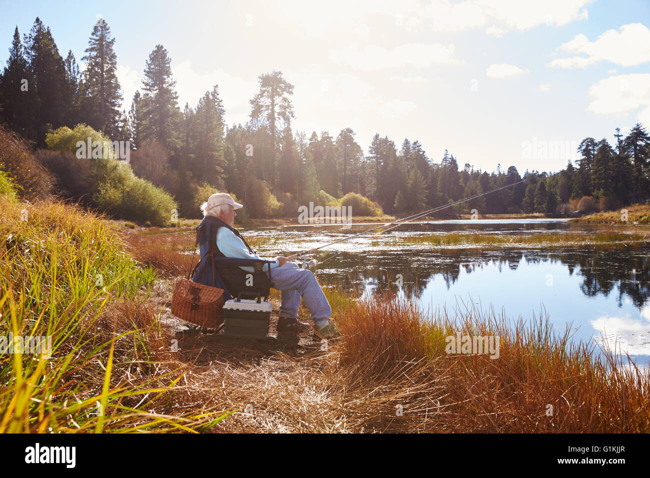 El hombre se sienta senior de pesca, Bluff, Big Bear Lake, California Foto de stock