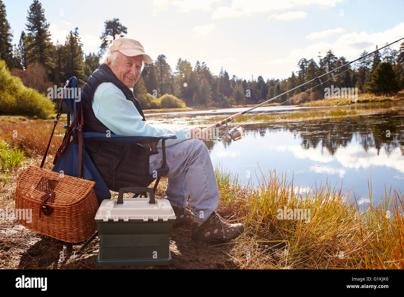 Hombre senior de pescar en un lago, mirando a la cámara, California Foto de stock