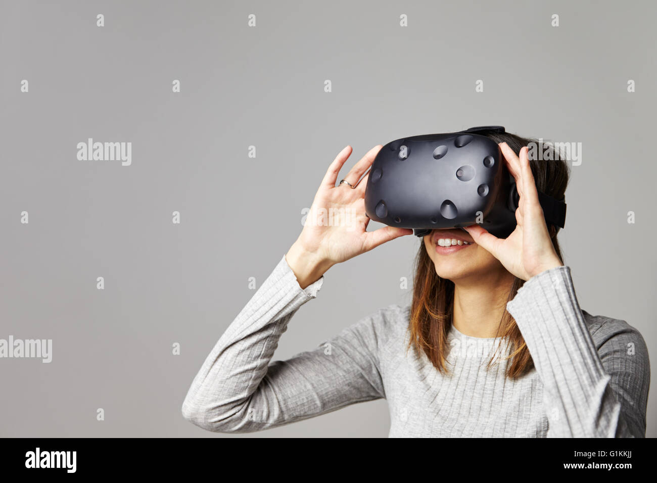Mujer sentada en un sofá en casa vistiendo casco de realidad virtual Foto de stock